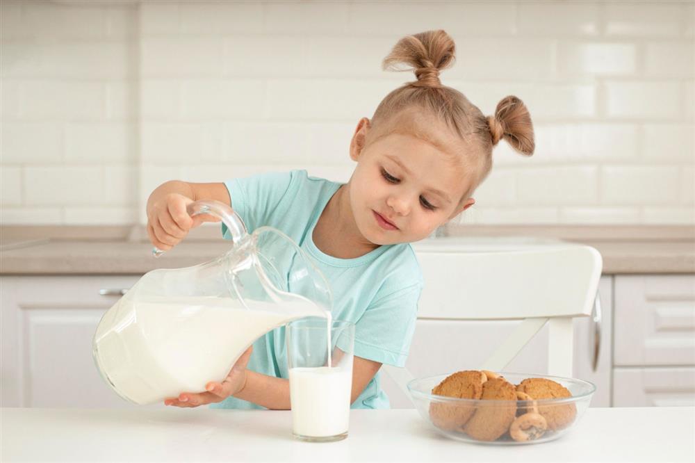 A little girl pouring milk into a glass